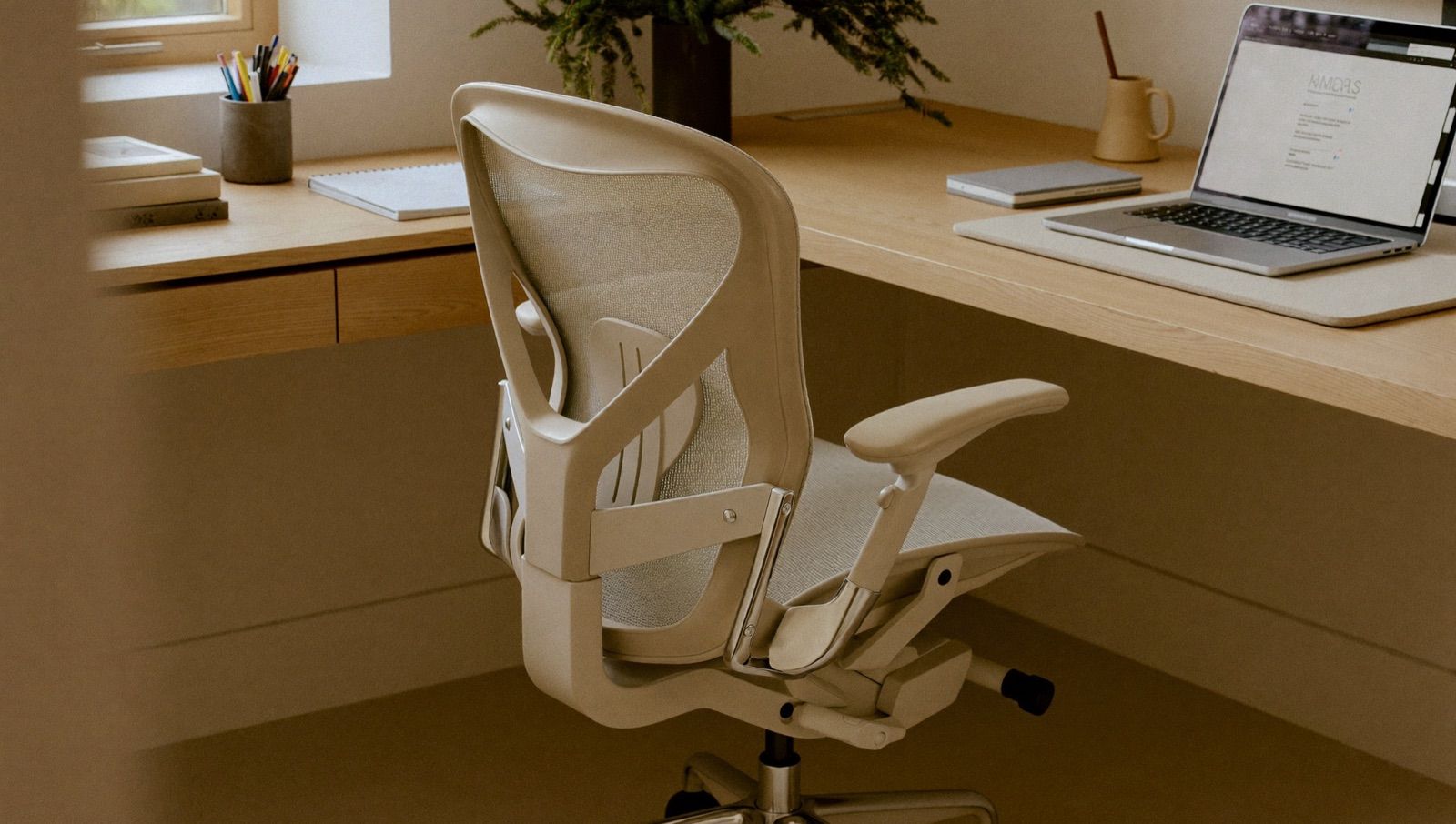 Ergonominen työtuoli valoisalla työpisteellä tietokoneen äärellä